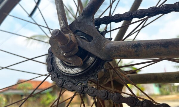 Detailed close-up of a weathered bicycle chain and rear wheel sprocket hub showing rusty metal components and mechanical texture