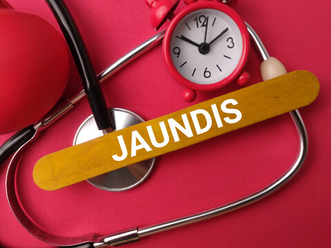 A yellow stick labeled JAUNDIS sits framed by a stethoscope, red clock, and ball on pink