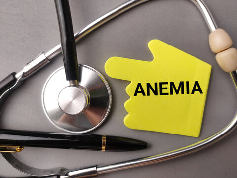 A yellow hand cutout labeled ANEMIA sits framed by a stethoscope and a black pen on gray