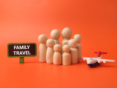 A group of wooden peg figures stands next to a toy airplane and a FAMILY TRAVEL sign on orange