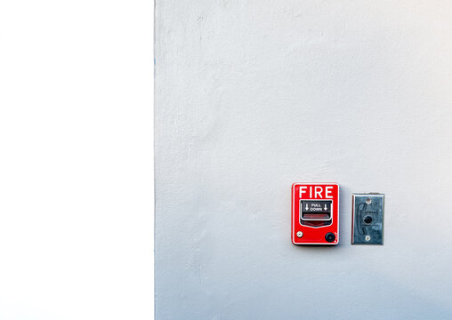 Red fire alarm pull station installed on an interior wall, representing emergency response, building safety, fire prevention systems and evacuation preparedness with large copy space for design use.