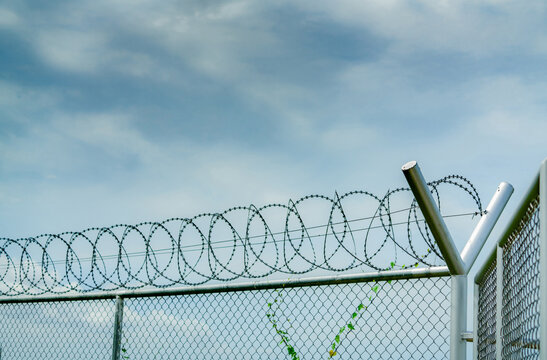 Prison security fence. Barbed wire security fence. Razor wire jail fence. Barrier border. Boundary security wall. Prison for arrest criminals or terrorists. Private area. Military zone concept.