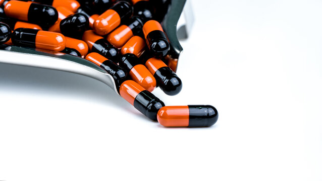 Orange-black capsule pills on drug tray. Antibiotics drug resistance. Drug use with reasonable. Antimicrobial capsule pills. Pharmaceutical industry. Infection treatment medicine in hospital.