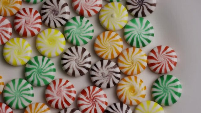 Colorful peppermint swirl candies rotating on a white plate