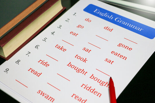 filling out English grammar worksheet with red pen