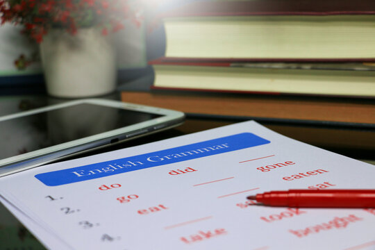 filling out English grammar worksheet with red pen