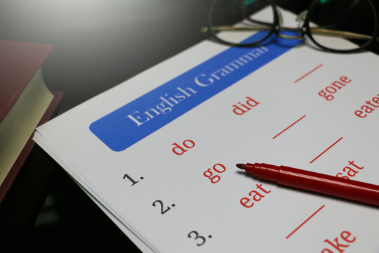 filling out English grammar worksheet with red pen