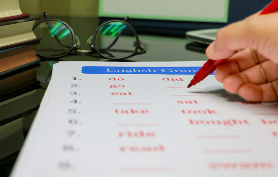 filling out English grammar worksheet with red pen