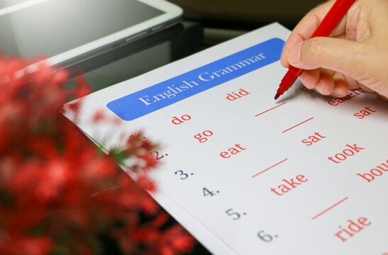 filling out English grammar worksheet with red pen