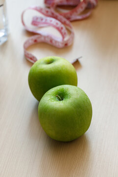 Two fresh green apples with a measuring tape in the background, representing healthy eating, balanced nutrition, weight management, fitness, and wellness lifestyle concepts