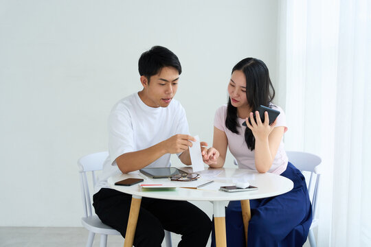 Young Japanese Man and Woman Discussing Household Finances at Table