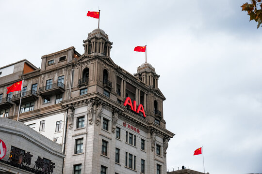 SHANGHAI, CHINA - DECEMBER 15, 2024: Low angle view of the historic AIA Building (former North China Daily News Building) decorated with Chinese national flags on The Bund.
