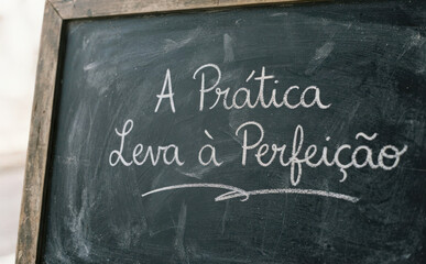 Fototapeta premium A Prática Leva à Perfeição lousa com frase motivacional em português para educação e foco