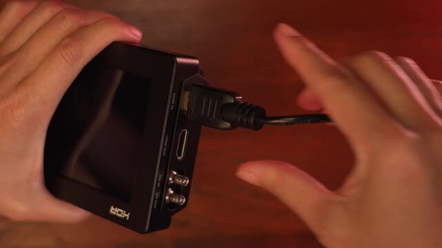 Close up shot of woman hands plugging HDMI cable into external monitor display port and unplugging, filmmaking technology and video output concept.