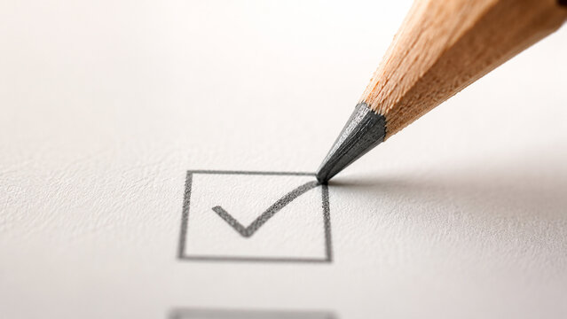 Macro shot of a pencil drawing a checkmark in a checkbox on paper