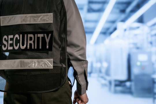 Close view of a security guard wearing a vest in a blurred airport terminal, safety, access control and travel protection.
