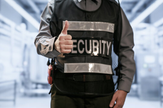 Close view of a uniformed security guard giving a thumbs up inside a modern transport terminal, safety, protection and trusted service.