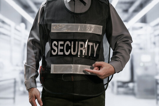 Close-up of a security guard wearing a protective vest in a bright modern building corridor, safety, access control, and professional protection.