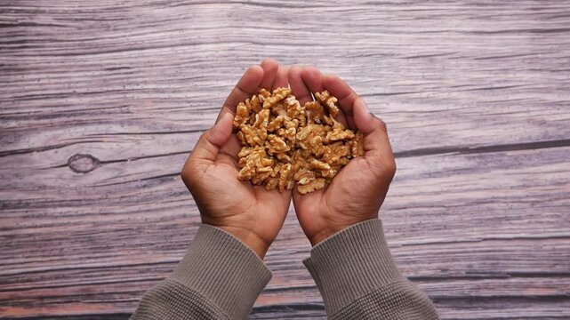 Holding walnuts in hands over wooden surface