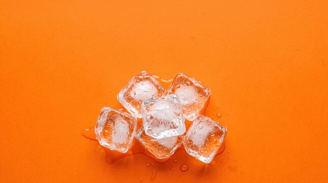Fresh transparent ice cubes melting with water droplets on vibrant orange, summer refreshment and cold drink suitable for beverage advertising, cocktail party invitation