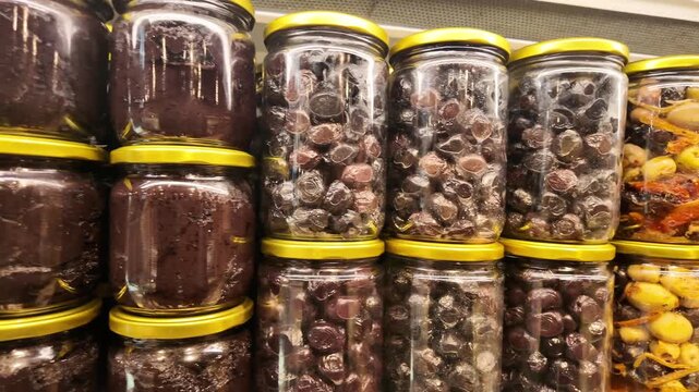 Rows of Glass Jars Filled with Olives and Olive Paste on Supermarket Shelves