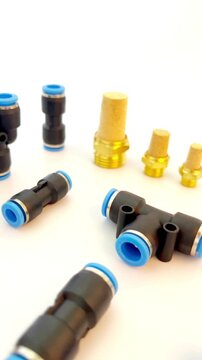 Assortment of metal and plastic pneumatic push in fittings and brass mufflers on white background