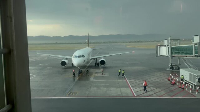 Commercial passenger airplane taxiing on a wet tarmac runway during overcast stormy weather,