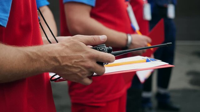 Close-up of emergency response team member holding a two way radio and clipboard while coordinating personnel during a rescue operation.