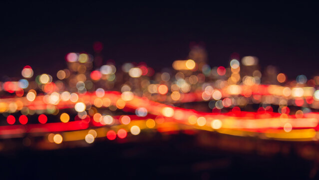 漆黒の空間に赤と黄の玉ボケが光跡を描く抽象的な都市の夜景シルエット背景
