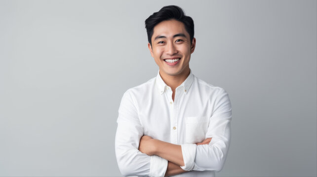 A Confident Smile: A young Asian man with a bright smile and arms crossed exudes confidence and professionalism.