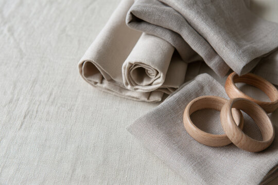 Neutral linen fabric with natural wooden rings arranged in a soft minimalist still life, highlighting textile texture, sustainable materials and copy space.