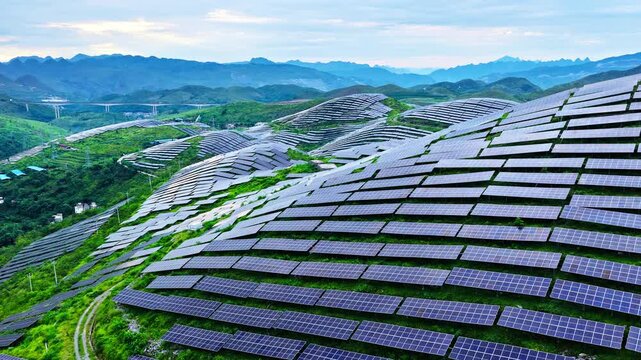Aerial view of a large-scale solar farm on green hills generating clean renewable energy in Guizhou, China