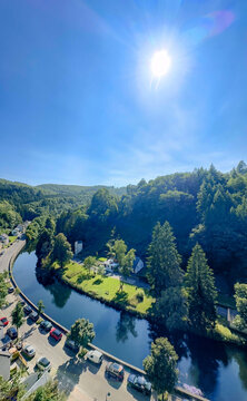 Esch-sur-Sure, Wiltz, Grand-Duche de Luxembourg, September 07, 2025, aerial river valley with sunlit gardens and winding water curve. elevated viewpoint shows clustered houses, manicured lawns,