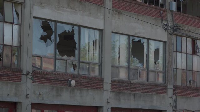 Shattered windows on the side of an abandoned warehouse. Destroyed factory. Industrial facility. 