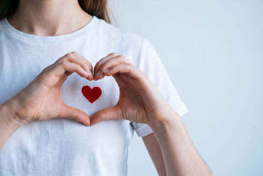 Woman making heart shape gesture with red heart symbol shirt