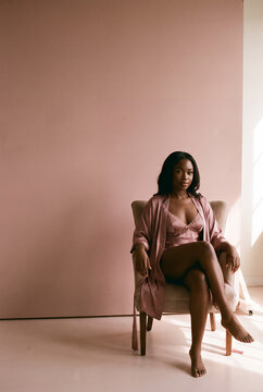 Woman in pink minimalist room sitting on chair beauty portrait