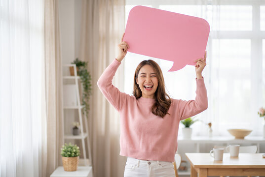 Happy woman holding pink speech bubble with copy space in bright home