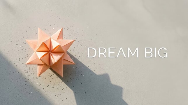 Pale peach origami star sits on a textured gray background with inspiring dream big white text