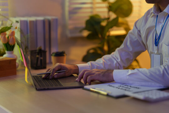 Cropped hands of businessman typing on laptop while working late at office desk