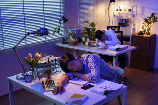 Asian businessmen sleeping at desk exhausted from working late in office