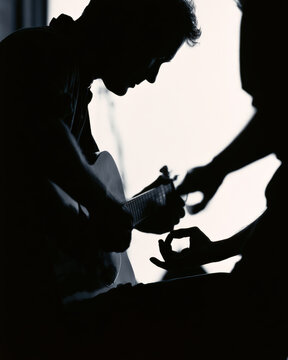 Silhouetted musician plays guitar with focus and passion