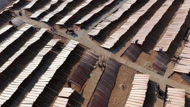 Aerial view of a worker drying traditional rice paper on bamboo racks in An Thai village, Binh Dinh, Vietnam