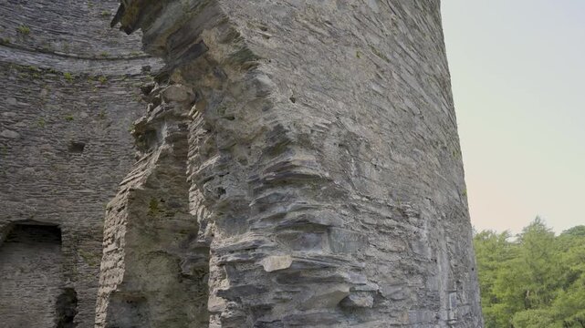 Detailed view of the outside of the Dolbadarn castle tower, camera moving upwards showcasing the details stone work of the ruins of the rounded tower and the door arch. 4k 30fps.
