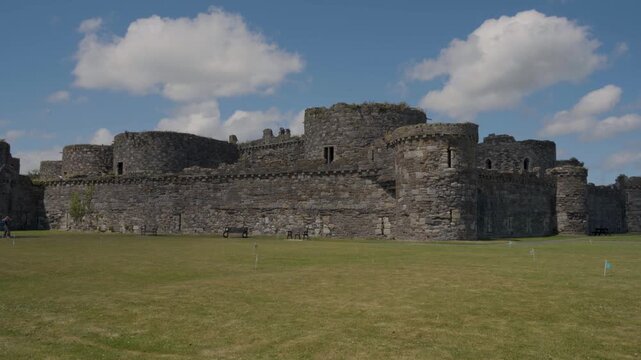 Beaumaris Castle in a peaceful Welsh landscape, featuring ancient stone walls, imposing towers, green grass and natural vegetation, capturing the timeless character of this historic Anglesey landma