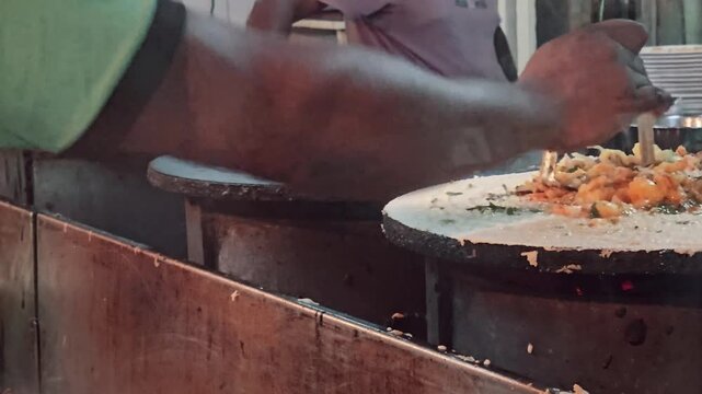 Chef preparing authentic Masala Dosa on hot flat iron griddles at an outdoor Indian street food stall, capturing themes of local culinary heritage, fast-paced cooking, and nighttime city lifestyle.
