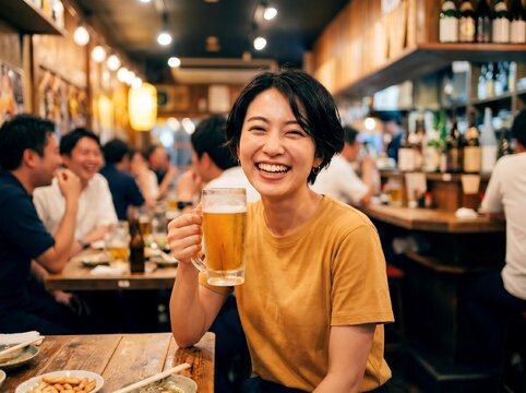 居酒屋のテーブルでビールジョッキを片手に満面の笑みを浮かべる日本人女性