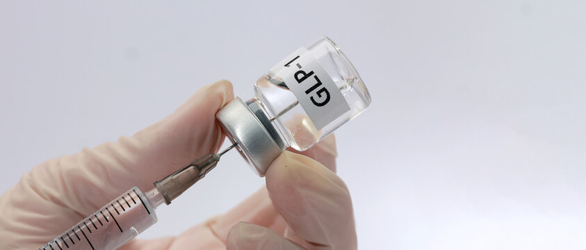 Gloved hand holds medical vial glp 1 syringe injection preparing liquid dose with focused hopeful patient care in clinic