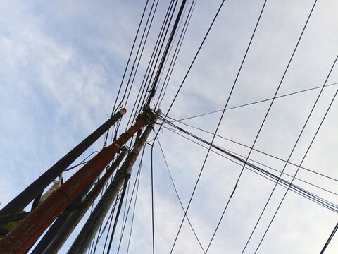 Disorganized network cables and tangled telecommunication wires hanging dangerously on a city street pole