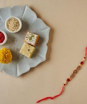 Rakhi with Indian Sweets, Rice, Kumkum and Marigold Flower