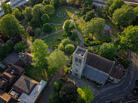 Public park Brenchley Gardens with Anglican church on a quiet sunny afternoon. Aerial view above the church surrounded by trees in green park. Golden hour sunlight. Maidstone, Kent, UK, 05.26.2026